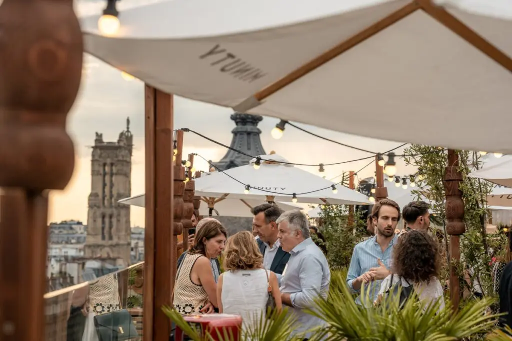 zoom sur un groupe d'invités en extérieur sur la terrasse avec ambiance guinguette, végétation et guirlandes