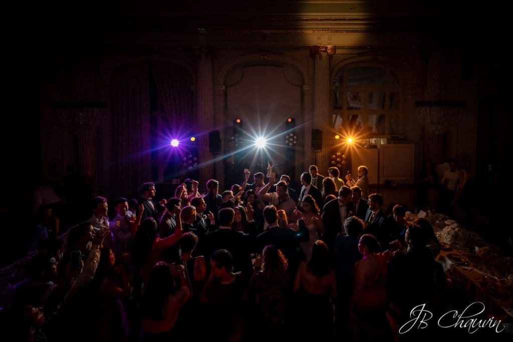 photo de soirée d'un mariage franco-américain au TRIANON PALACE de Versailles, plan large de la salle montrant les convives en train de danser