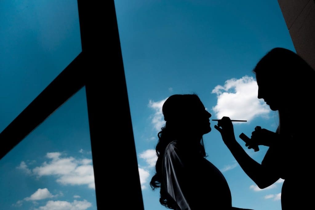 mariée à la fenêtre pendant les retouches maquillage au TRIANON PALACE de versailles