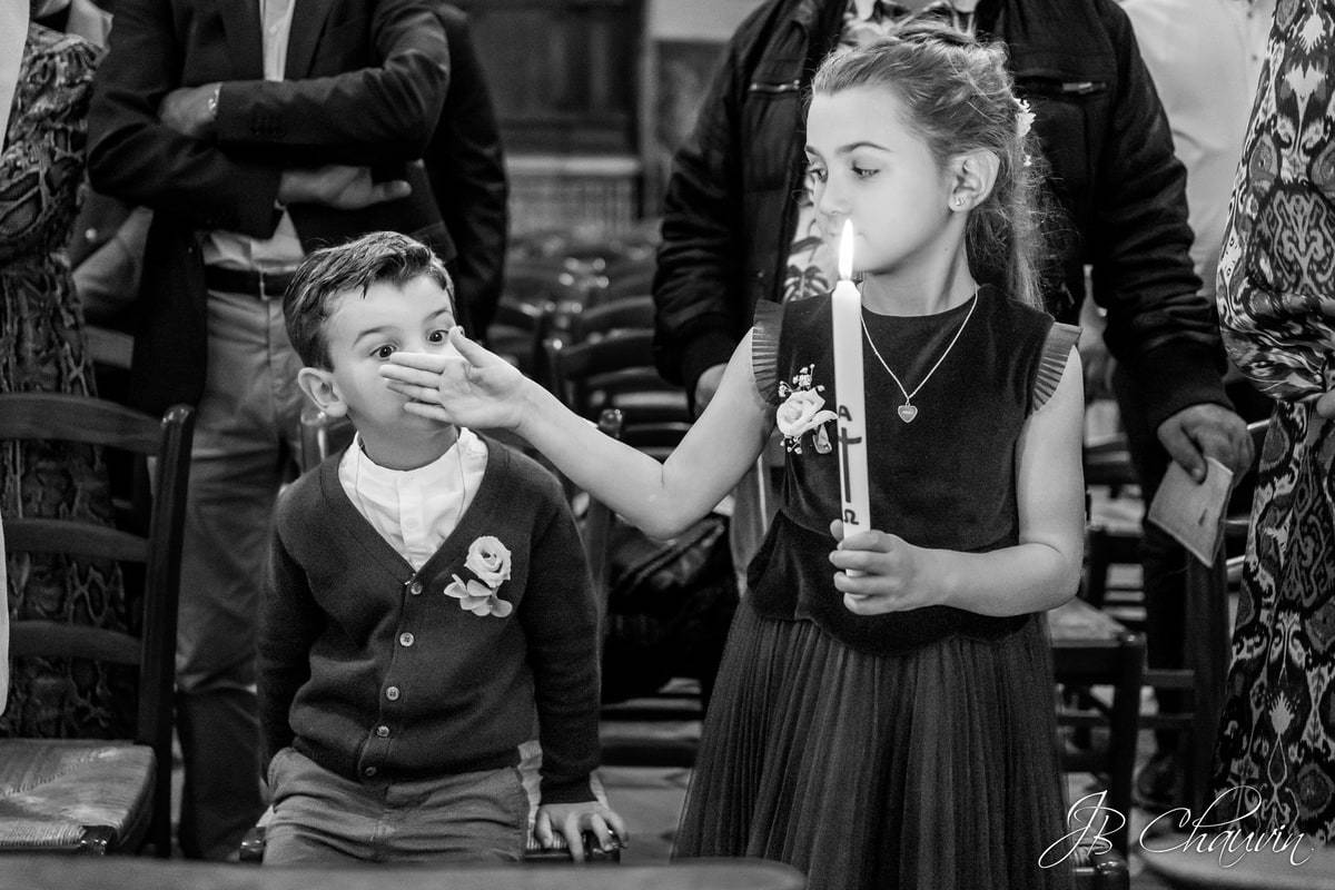 enfant en train de jouer avec une bougie dans une église pendant une cérémonie de baptême