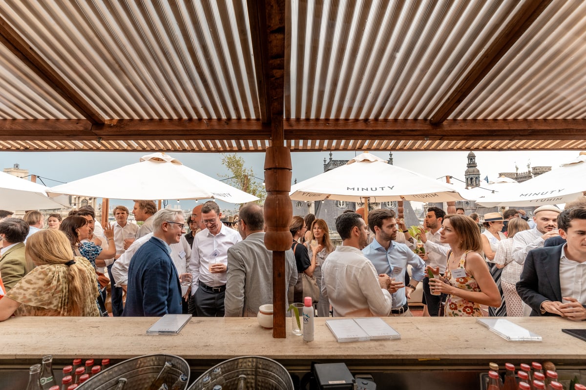 Invités échangeant autour du bar de Terraza Mikuna pendant un cocktail sur le rooftop du BHV Le Marais à Paris.