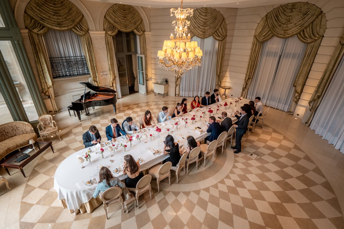Participants attablés autour d’une grande table de banquet dans un salon circulaire du Ritz Paris place Vendôme.