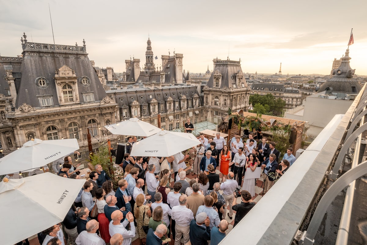 Invités réunis sur la terrasse Terraza Mikuna avec vue sur l’Hôtel de Ville et la tour Eiffel à Paris.