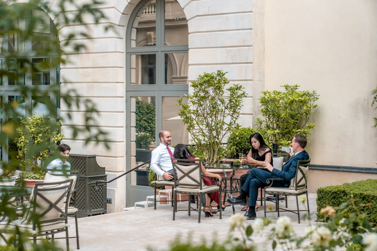 Petit groupe d’invités réuni autour d’une table sur la terrasse intérieure du Ritz Paris pendant un événement privé.