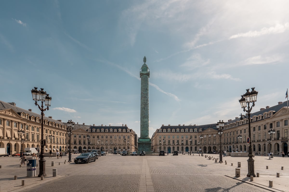 Vue de la place Vendôme à Paris avec la colonne Vendôme au centre et les façades historiques autour de la place.