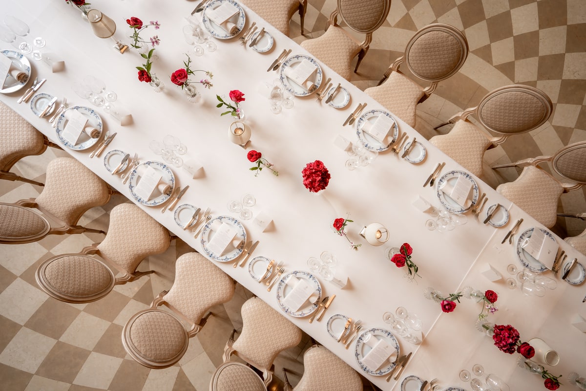 Vue en plongée d’une table de banquet au Ritz Paris avec vaisselle, décoration florale et assises élégantes.
