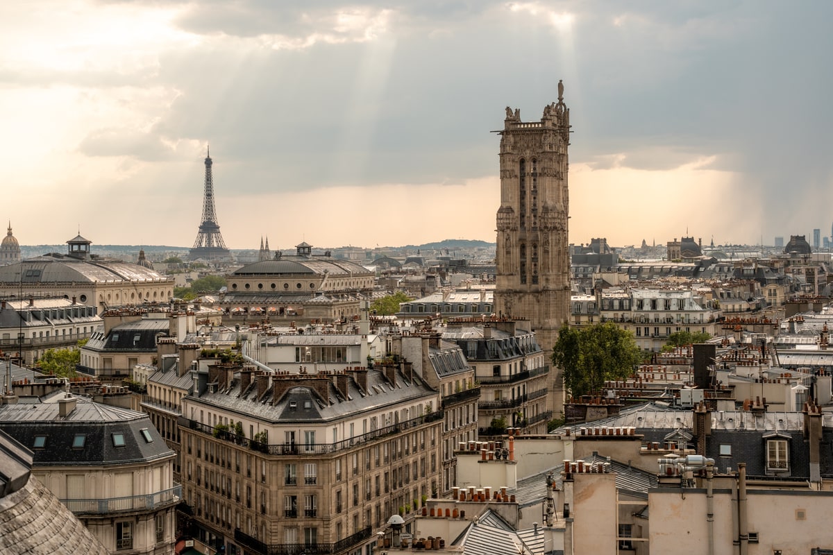 Vue de jour depuis Terraza Mikuna sur la tour Saint-Jacques et la tour Eiffel sous une lumière d’orage à Paris.